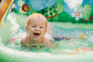 child plays in the pool. Little girl in the pool, smiling child